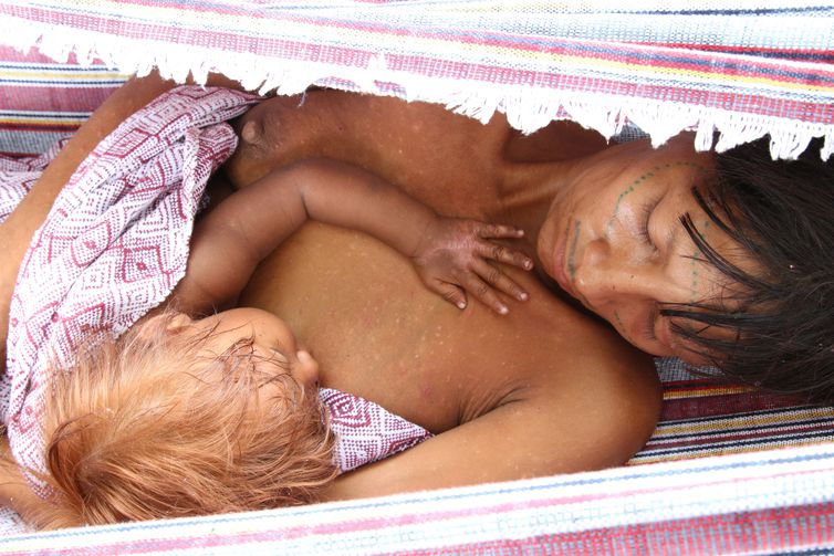 Boa Vista (RR), 13-02-2023, Mulher yanomami alimenta o filho em rede no acampamento montado às margens da BR-174 onde vive a família. Eles contam que andaram mais de 10 dias para chegar em Boa Vista.